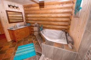 y baño con bañera y lavamanos. en Le Chalet Le Bois Rond Des Ruisseaux, en Saint-Tite-des-Caps
