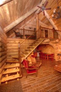 una escalera de caracol en una cabaña de madera con sillas rojas en Le Chalet Le Bois Rond Des Ruisseaux, en Saint-Tite-des-Caps