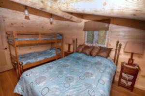 a bedroom with two bunk beds in a log cabin at Le Chalet Le Bois Rond Des Ruisseaux in Saint-Tite-des-Caps