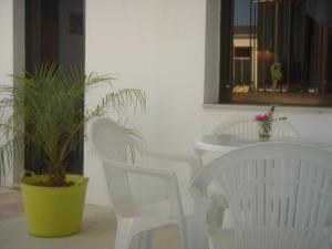 two white chairs and a table with a potted plant at Iliaktida Apartments in Kolymvari