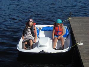 dos chicas sentadas en un pequeño bote en el agua en Le Chalet Bois Rond Relax, en Saint-Tite-des-Caps