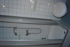 a white tiled bathroom with a tub and a toilet at Ferienwohnung Duß in Niederalteich