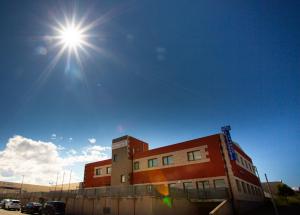 a building with the sun shining in the sky at Hotel Villa De Cárcar in Cárcar