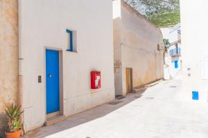 an alley with a blue door and a red fire hydrant at Cala Dogana Guest House in Levanzo