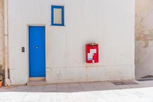 a blue door and a red box on a wall at Cala Dogana Guest House in Levanzo