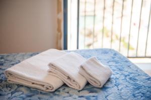 a pile of towels sitting on top of a bed at Cala Dogana Guest House in Levanzo