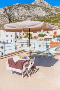 a table and chairs under an umbrella on a beach at Cala Dogana Guest House in Levanzo