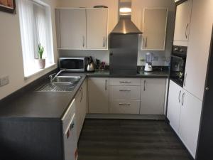 a kitchen with white cabinets and a sink at Alphalink Lodge in Middlesbrough