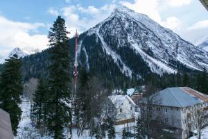 einen schneebedeckten Berg mit einem Gebäude davor in der Unterkunft Andersen Hotel in Dombai
