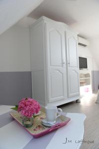 a table with a vase of pink flowers and a cup at La Bigourd'in in Escoubès-Pouts