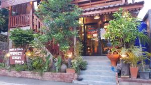 Un bâtiment avec une bande de plantes devant lui dans l'établissement Perfect Resort & motorbikes for rent Sukhothai, à Sukhothaï