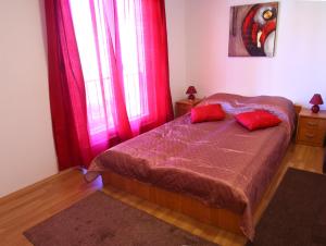 a bedroom with red curtains and a bed with two red pillows at Guesthouse Liska in Mostar