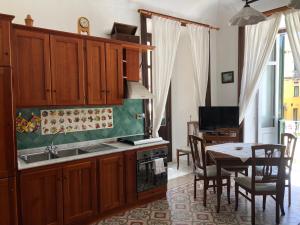 a kitchen with wooden cabinets and a table and a dining room at Residenza Amante Center in Tropea