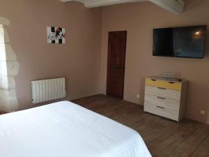 a bedroom with a white bed and a flat screen tv at Le Domaine de Bella in Dangé