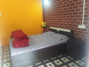 a room with a small bed with a brick wall at VAMOOSE YOLMO in Mirik
