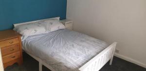 a small bedroom with a white bed and a wooden dresser at Snowdonia miners cottage in Blaenau-Ffestiniog