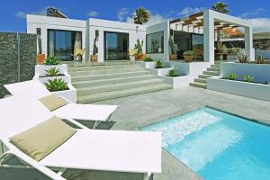a villa with a swimming pool and white furniture at Villa Casajable in Pájara