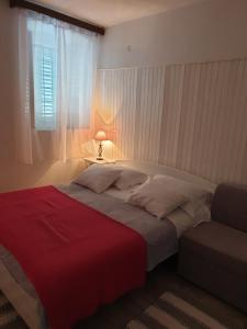 1 dormitorio con 1 cama con manta roja y ventana en Apartments Neda, en Drače