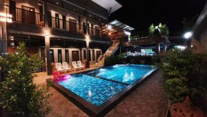 una piscina frente a un edificio por la noche en The Nature Sukhothai, en Sukhothai