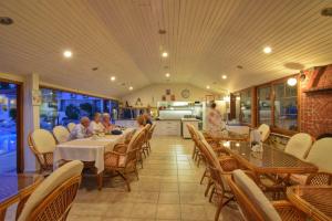 a dining room with people sitting at tables in a restaurant at Olympos Hotel - Adults Only in Ovacik