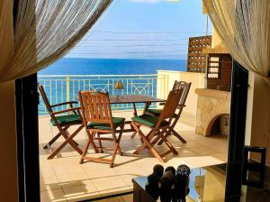 a balcony with a table and chairs and the ocean at Derveni Seaside Apartments - Deluxe Sea View Penthouse Jacuzzi-BBQ & Groundfloor Garden View Apartment in Derveni