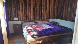 a bed in a room with a wooden wall at Vamoose Sunakhari in Mirik