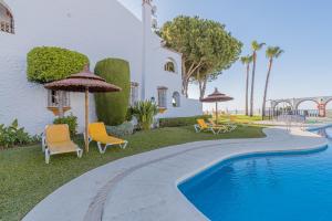 a swimming pool with chairs and umbrellas next to a house at Tio Charles in Benalmádena