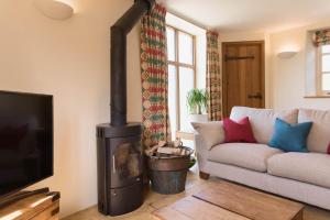 a living room with a couch and a wood stove at Cottage 1 New Yatt Farm in Wilcote