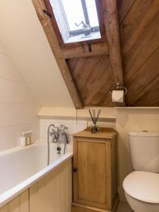 a bathroom with a toilet and a tub and a window at Cottage 1 New Yatt Farm in Wilcote