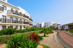 a person walking down a path in front of a building at Sol Dunas - All Inclusive in Santa Maria