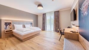 a bedroom with a bed and a desk and a television at Heuboden Hotel Heu.Loft Freiburg in Umkirch