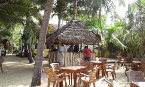 a man standing in front of a restaurant with tables and chairs at Shashini Beach Resort in Arugam Bay