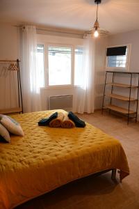1 dormitorio con 1 cama con colcha amarilla y ventana en L'Oiseau Bleu, en Tournon-sur-Rhône