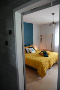 um quarto com uma cama com uma colcha amarela em L'Oiseau Bleu em Tournon-sur-Rhône