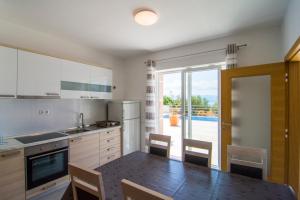 a kitchen with a dining table and a view of a pool at Villa Nikola - pool side apartments in Bol