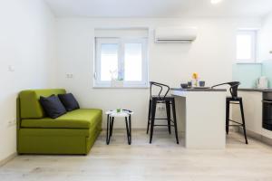 salon z zieloną kanapą i kuchnią w obiekcie 2sis apartments w mieście Zadar