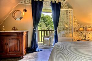 1 dormitorio con 1 cama y una ventana con cortinas azules en Les Fermes de Florence Bien être et nature en Les Champeaux
