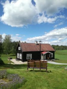uma casa negra com um banco à frente. em Presterudveien 125 em Vikersund