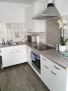 una cocina con armarios blancos y fregadero en Carina Apartment, en Kandern