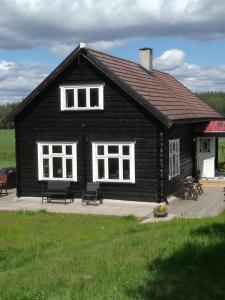 a black house with benches in front of it at Presterudveien 125 in Vikersund