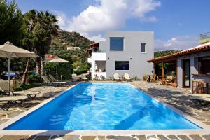 a villa with a swimming pool in front of a house at IRIDA Guesthouse by the Pool in Plakias