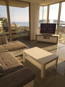 uma sala de estar com uma televisão, um sofá e uma mesa em Lunde Sea View Apartment em Rafailovici