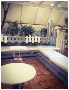 una stanza con panche e tavoli bianchi e piante di B&B La Giara a Porto Empedocle