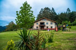 una casa vieja en un campo con parque infantil en Apartamentos Rurales Larrago, en Busturia