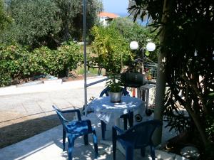 een tafel met blauwe stoelen en een tafel met een plant erop bij House Mantesos in Koinira