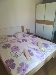 a bedroom with a bed with purple flowers on it at Apartments Ivanka in Ston