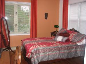 a bedroom with a bed with red curtains and a window at Magnolia B&B in Granby
