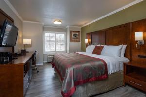 Habitación de hotel con cama, escritorio y TV. en Ramada by Wyndham Mountain View, en Mountain View