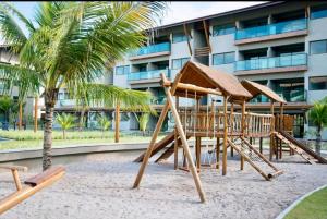 un parco giochi di fronte a un edificio con una palma di Flat Polinésia Térreo Piscina Privativa a Porto De Galinhas