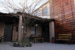 een gebouw met een bank en een boom ervoor bij hostal iquisa in San Pedro de Atacama